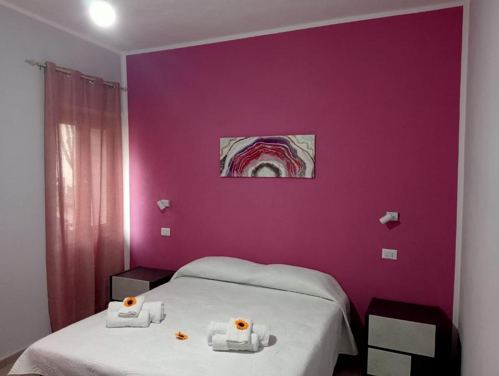 1 dormitorio con paredes moradas y 2 camas con toallas en CASA DEL CORSO, en Dorgali