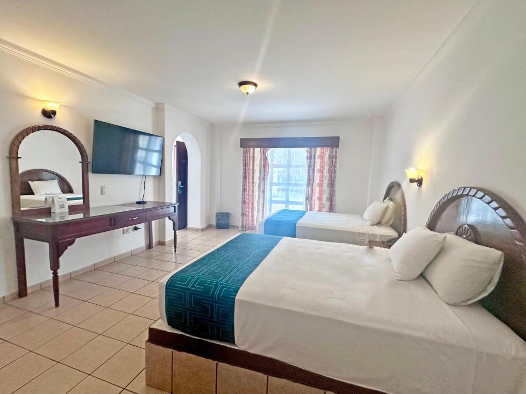 クリアカンにあるInHouse Select Hacienda Tres Riosのベッド2台とデスクが備わるホテルルームです。