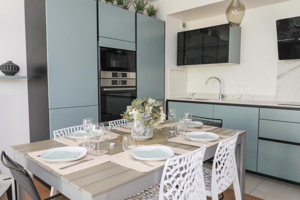 uma sala de jantar com mesa e cadeiras e uma cozinha em Le Cèdre, appartement neuf et décoration soignée em Fontenay-sous-Bois
