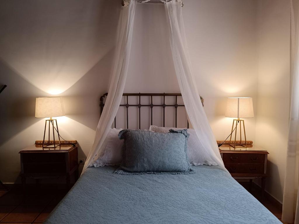 1 dormitorio con 1 cama con dosel y 2 lámparas en Apartamentos Turisticos La vida de antes, en Consuegra
