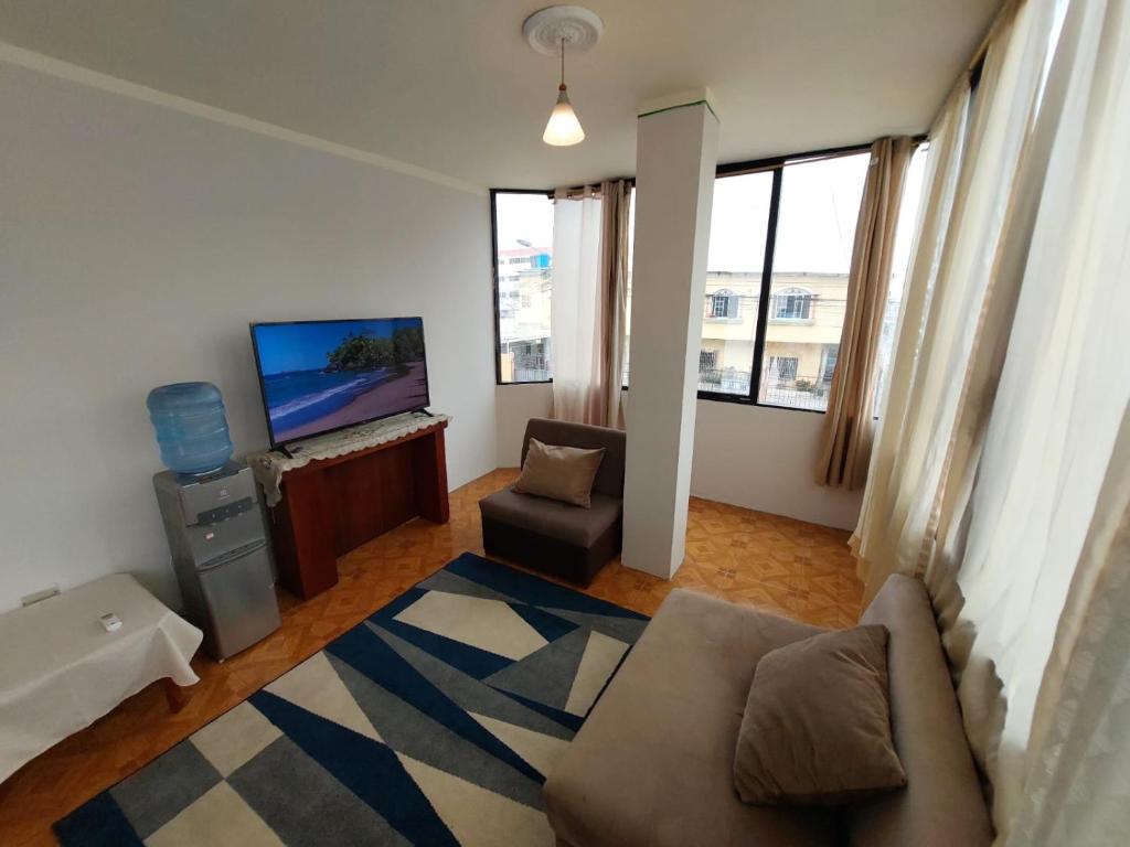 ein Wohnzimmer mit einem Sofa und einem TV in der Unterkunft Departamentos de la Costa in Machala