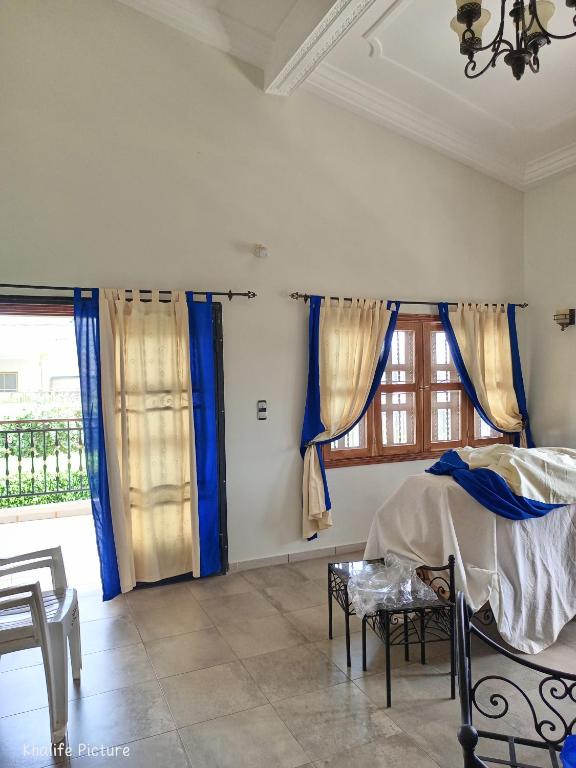 a bedroom with blue curtains and a bed and a window at Résidence cœur de Marie in Abomey-Calavi