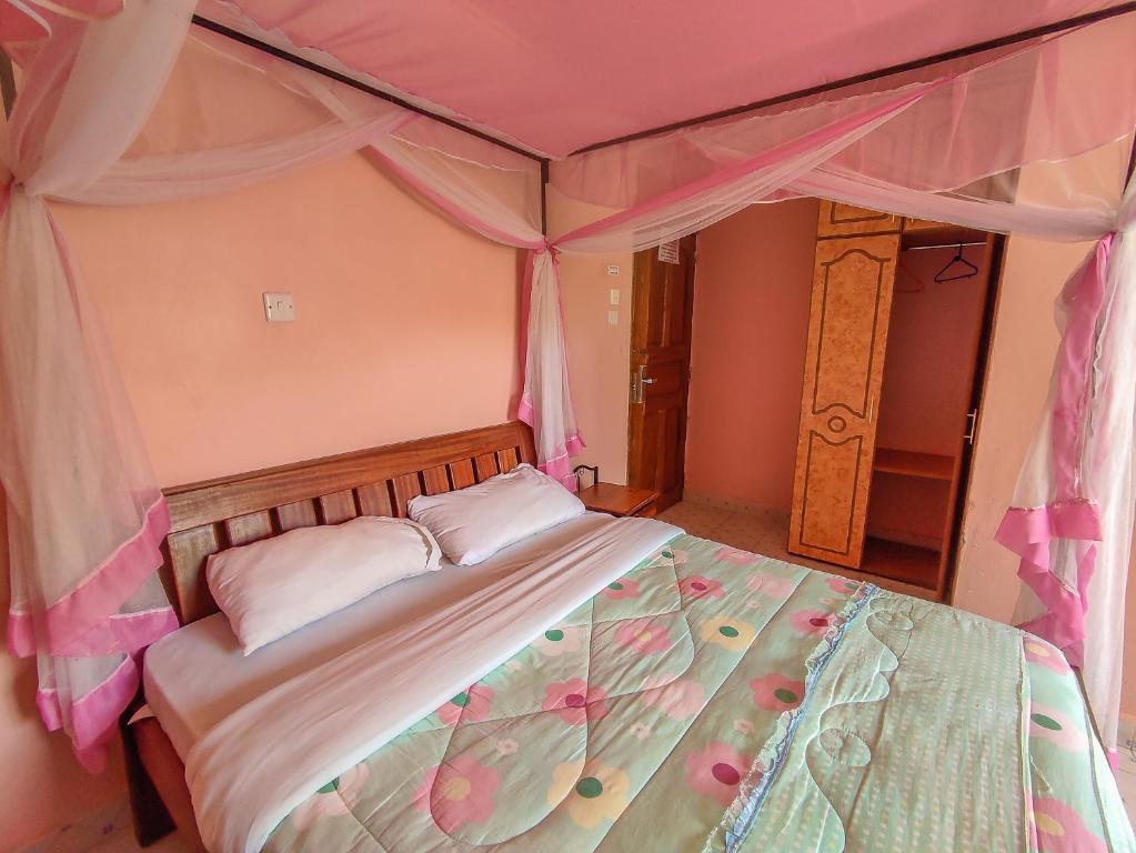 Un dormitorio con una cama con dosel y flores. en Sunciti Resort Sagana 