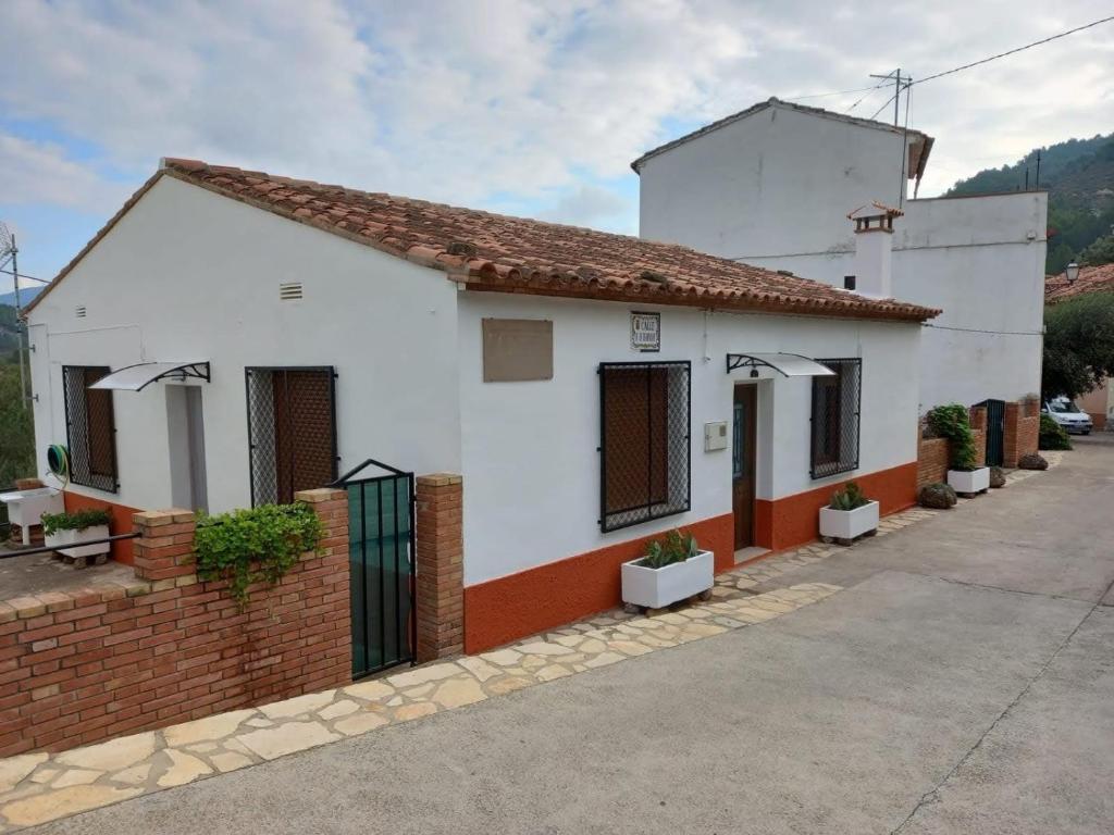 une maison blanche et rouge avec un mur en briques dans l'établissement La casita de la Alquería, Montanejos, à Montanejos