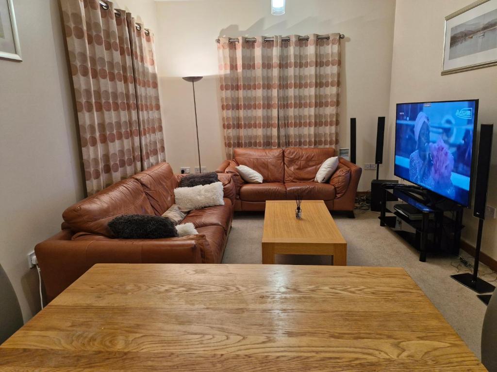 a living room with brown leather couches and a tv at Impeccable 1-Bed Apartment in Purfleet in Purfleet