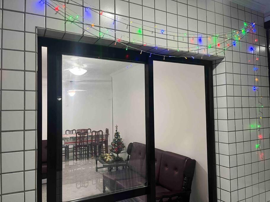 a reflection of a dining room with christmas lights on the wall at Apartamento com vista do mar in Praia Grande
