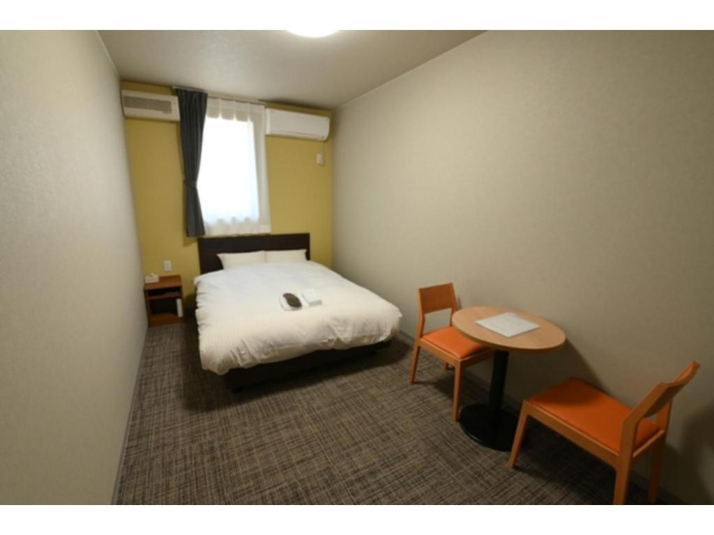 um quarto com uma cama, uma mesa e cadeiras em Ｓｗｉｍｍｙ Ｉｎｎ Ｏｎａｇａｗａ - Vacation STAY 56625v em Onagawa