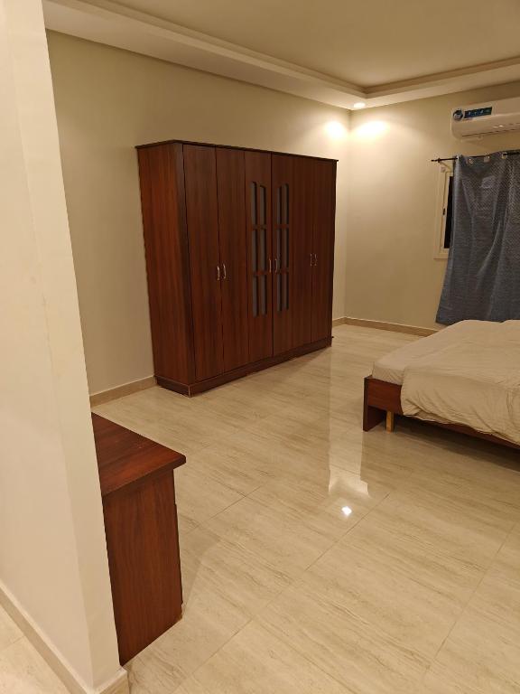 a bedroom with a bed and a wooden cabinet at حي المطار King Khalid Airport Community Apartment in Riyadh