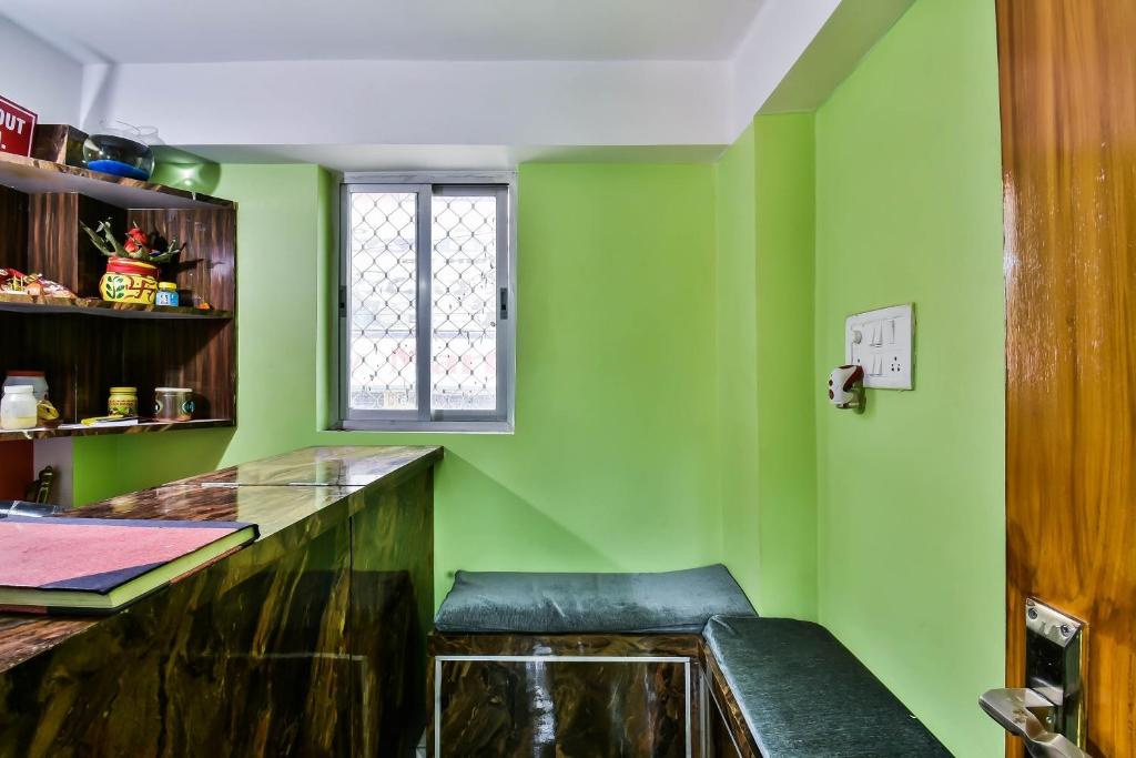 uma cozinha verde com um banco e uma janela em OYO RP Palace Inn em Dānāpur