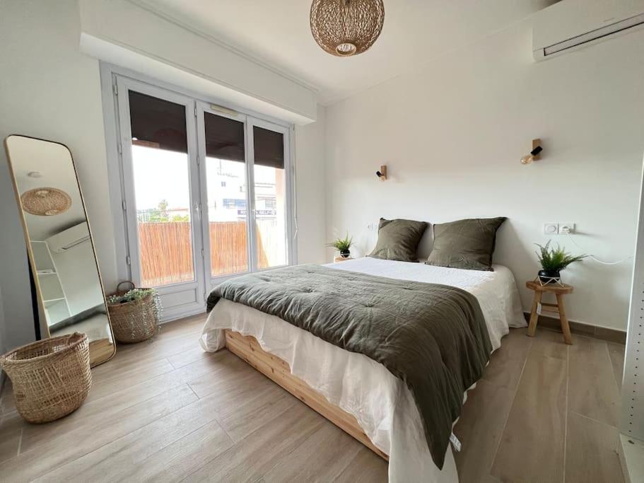 une chambre avec un grand lit et une grande fenêtre dans l'établissement T2 tout confort proche plage, à Antibes