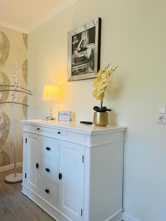 a white cabinet with a vase of flowers on it at Maison Lily Apartment 5 in Bad Lauterberg