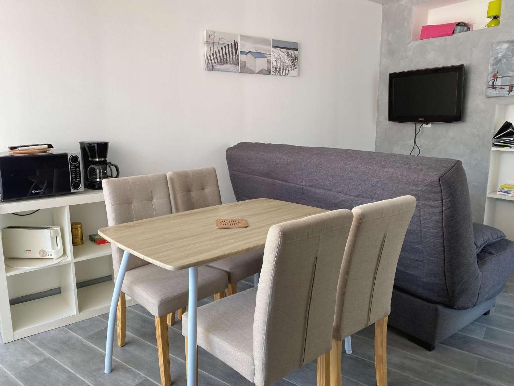 - une table à manger avec des chaises et un canapé dans l'établissement Beau T2 rénové avec balcons, climatisation et proche des Thermes - Balaruc-les-Bains - FR-1-553-115, à Balaruc-les-Bains