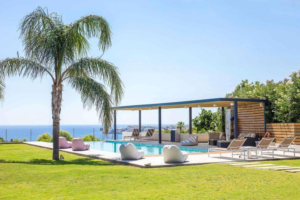 a swimming pool with chairs and a palm tree at RLM Prime Beach Panoramic Villa in Kolimbia