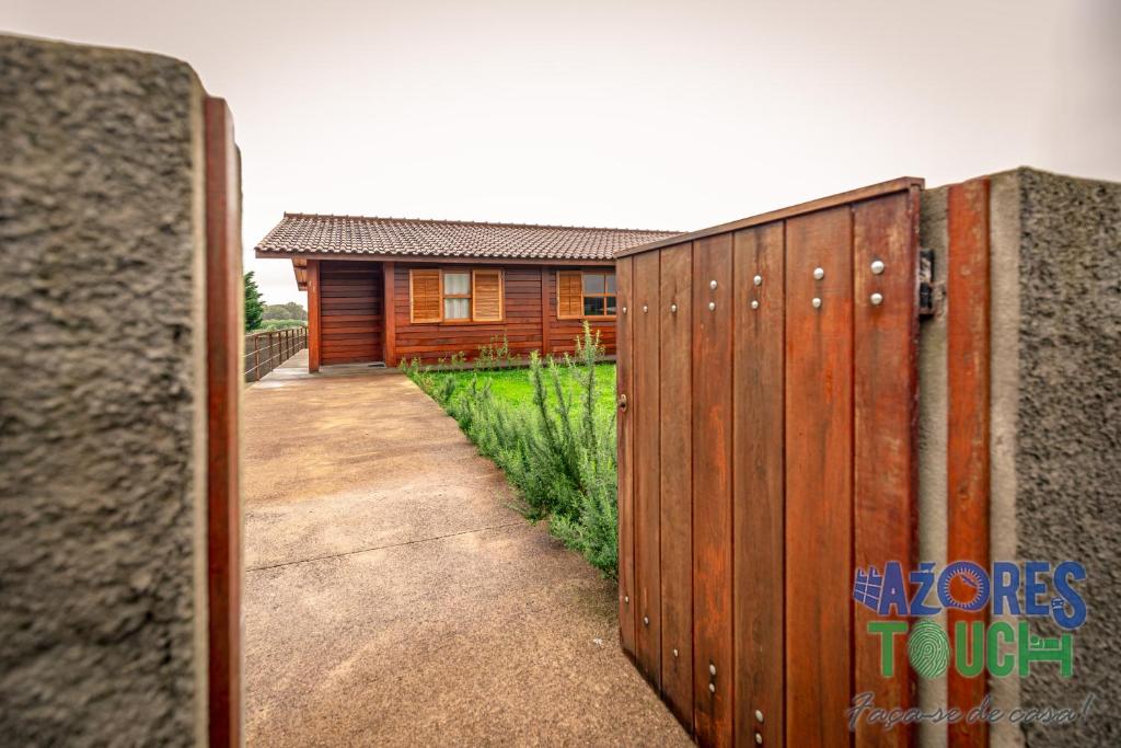 a wooden fence with a house in the background at Casa da Fontinha in Praia da Vitória