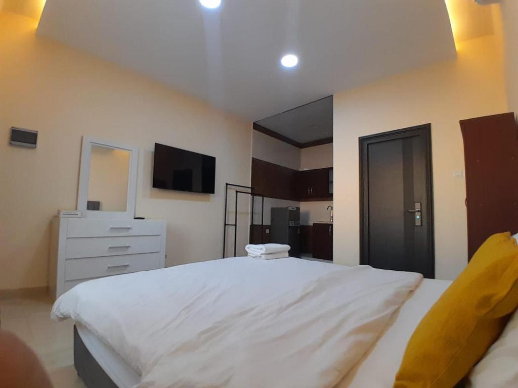 a bedroom with a large white bed and a tv at EK Homes in Ras al Khaimah