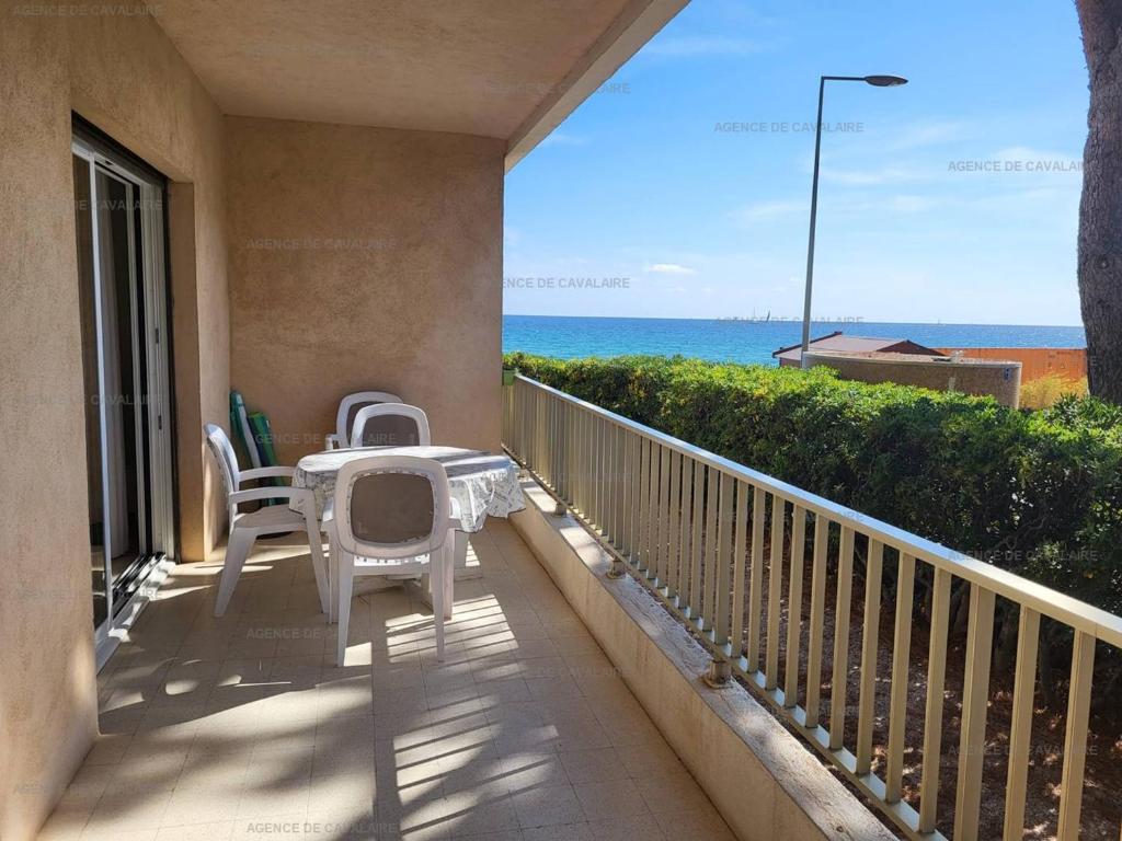 un balcon avec une table et des chaises et l'océan dans l'établissement Appartement pieds dans le sable au Parc de Cavalaire - Climatisé - FR-1-100-248, à Cavalaire-sur-Mer