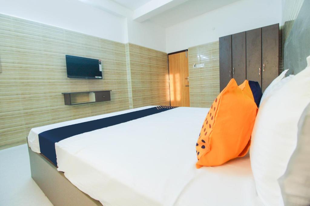 a bedroom with a large white bed with an orange pillow at Flagship Jp Residency in Singapperumālkovil