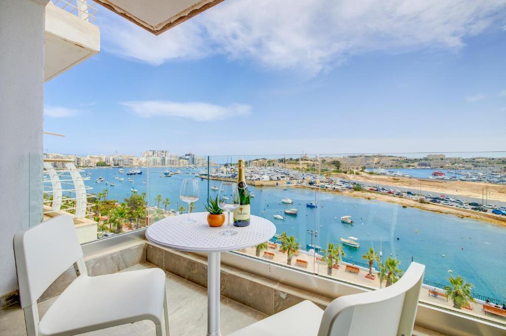 een balkon met een tafel en stoelen en uitzicht op het water bij Stunning Apartment with Valletta and Harbour Views in Sliema