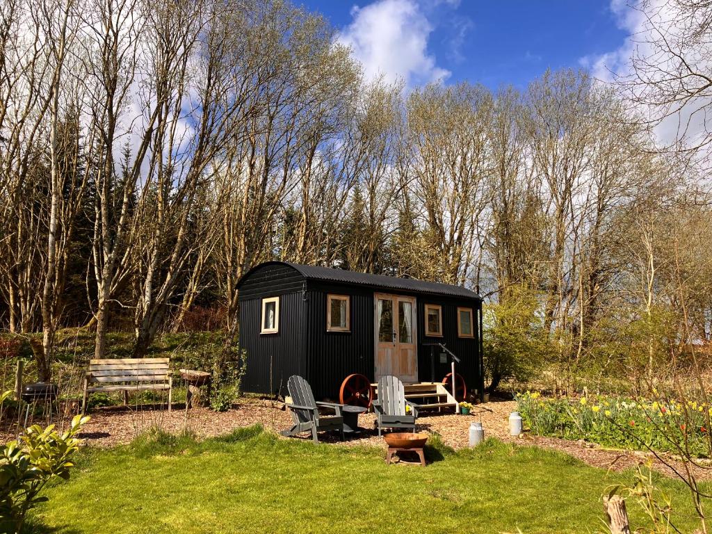 uma pequena casa preta no meio de um quintal em Archie the shepherd’s hut em Penruddock
