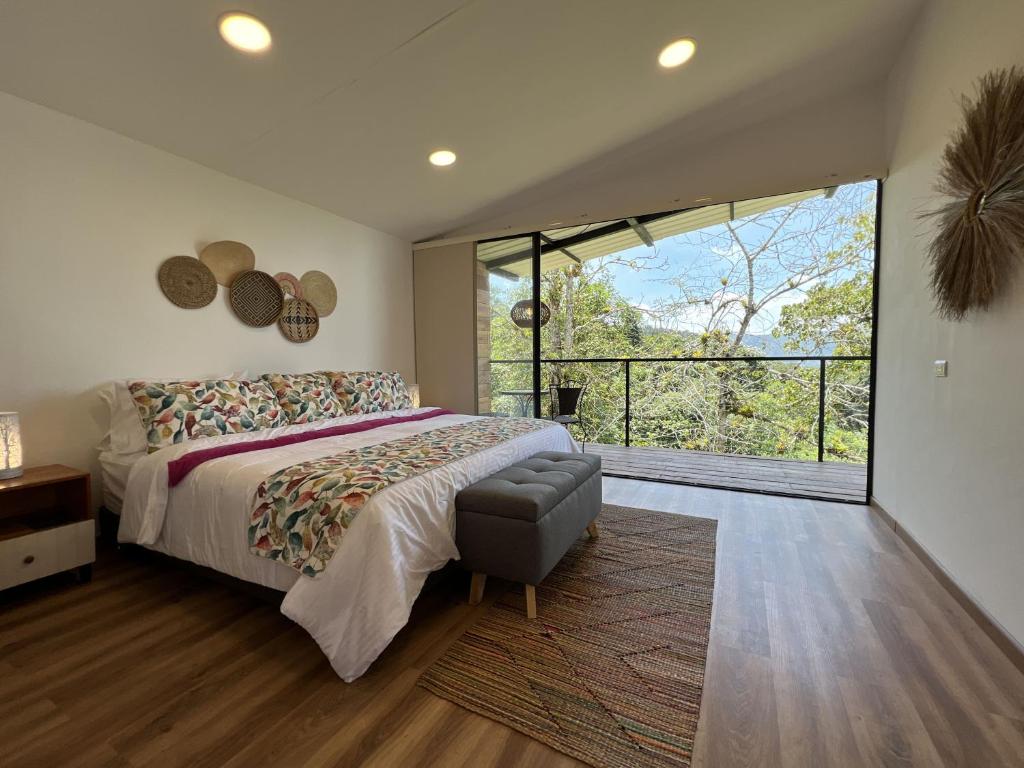 ein Schlafzimmer mit einem großen Bett und einem großen Fenster in der Unterkunft San Felipe Lodge. Birding and Wellness in Cali