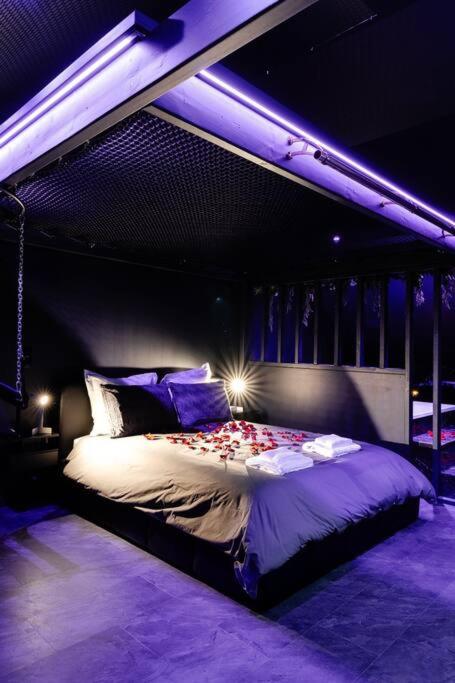 1 dormitorio con 1 cama grande con iluminación púrpura en Bisou X, nuits érotiques & spa., en Biéville-Beuville