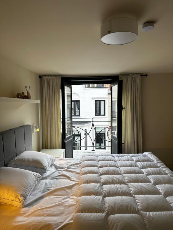 a large white bed in a bedroom with a window at Villa Frans Luxe appartement 4 slpk in Ostend