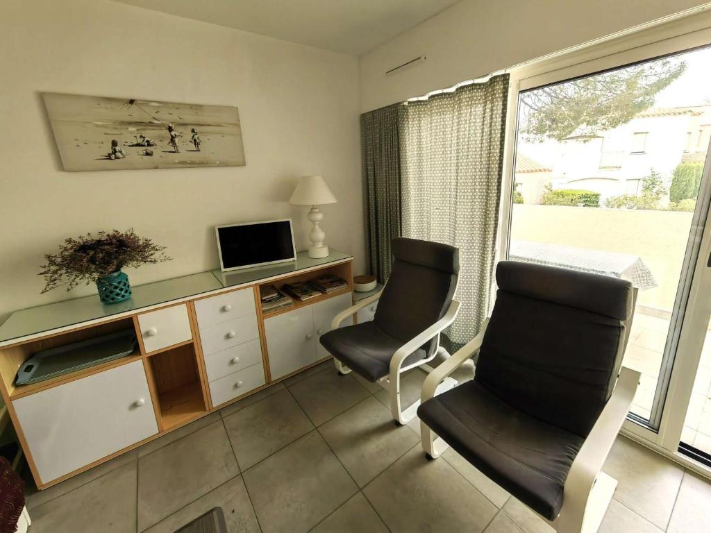 - un salon avec deux chaises, un bureau et une télévision dans l'établissement T3 rénové avec clim, piscine et parking à 100m de la mer - FR-1-607-24, au Cap d'Agde