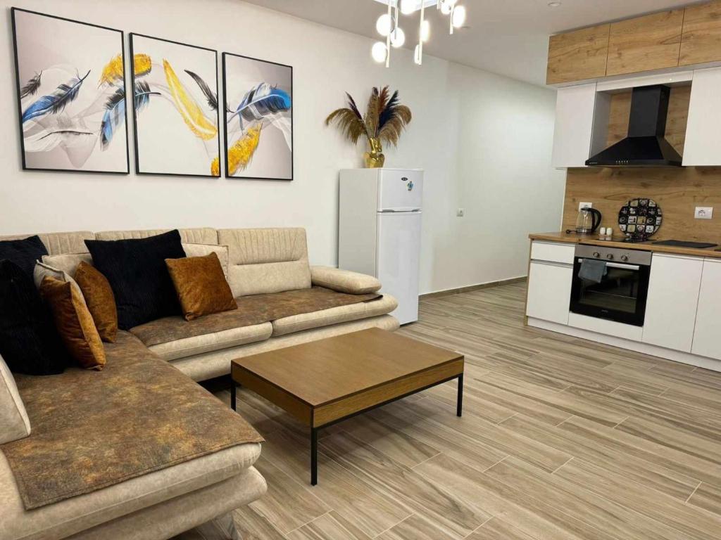 a living room with a couch and a table and a kitchen at oasis apartment in Sarandë