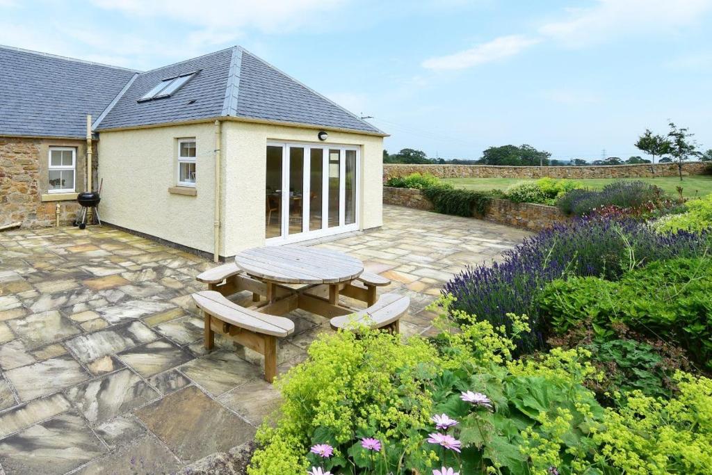 a patio with a table and benches in a garden at Hawthorn House in Pathhead