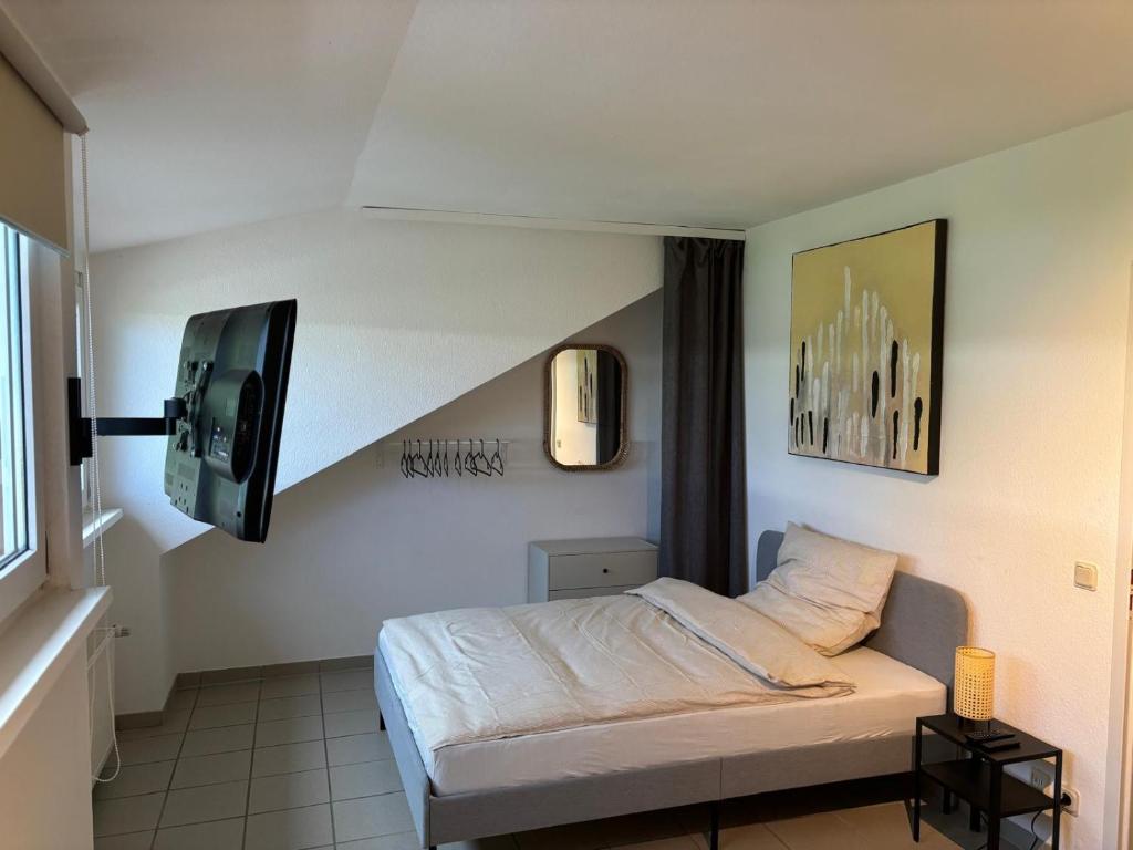 1 dormitorio con 1 cama y TV en la pared en Wohnen in der Natur, en Saarbrücken