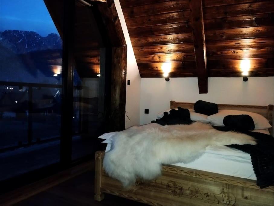 a bedroom with a bed with white sheets and fur at Domki TATRA HOMES z jacuzzi in Kościelisko