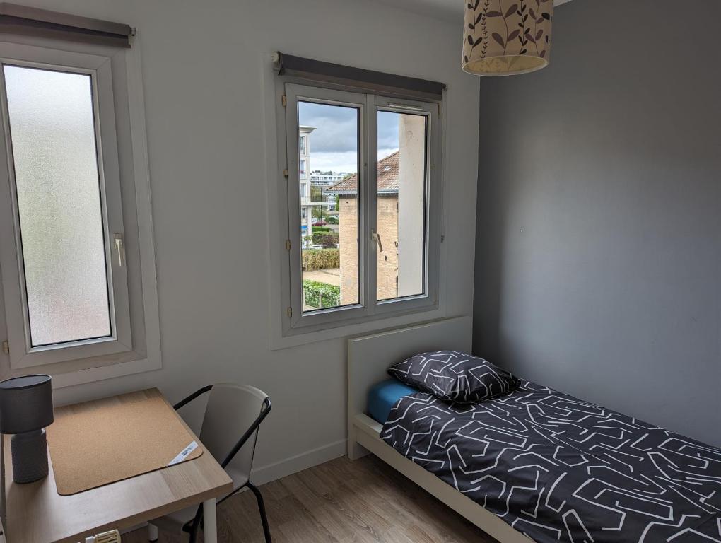 a bedroom with a bed and a desk and two windows at Chambre cœur du centre-ville in Le Havre