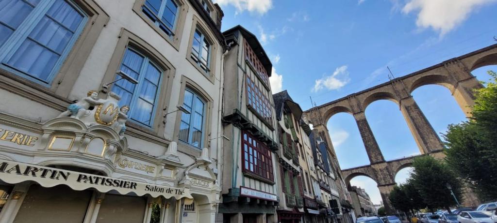 an old building with a bridge in the background at Au Pied du Viaduc in Morlaix