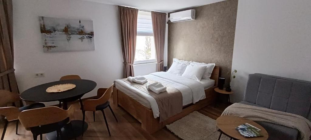 a bedroom with a bed and a table and a window at Studio apartman Peti in Varaždin