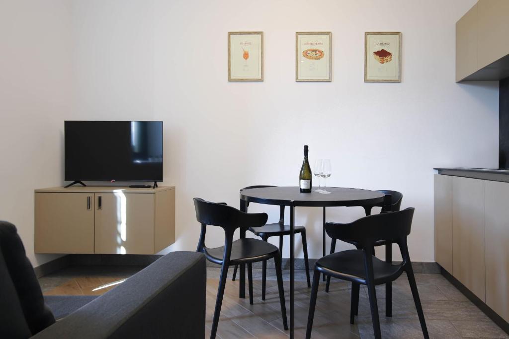 una sala da pranzo con tavolo, sedie e TV di Cà del Lasco - Modern Apartments in Classic Villa a Bellano