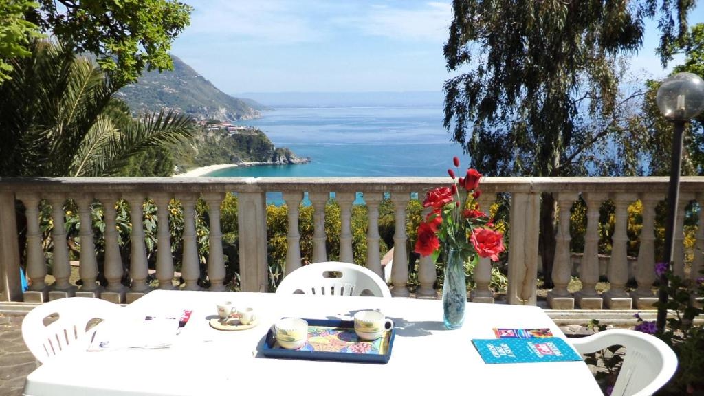 Una mesa con un jarrón de flores en un balcón. en Villa del Capo, en Capo Vaticano