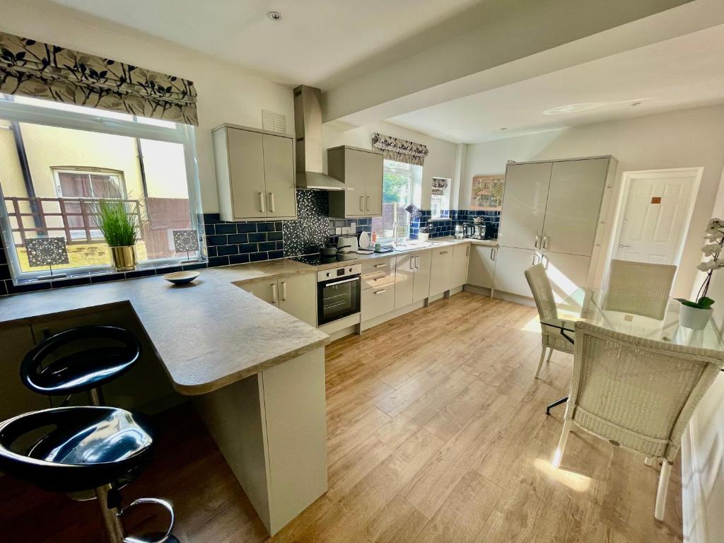 a kitchen with white cabinets and a table and chairs at Golden Triangle Townhouse in Norwich