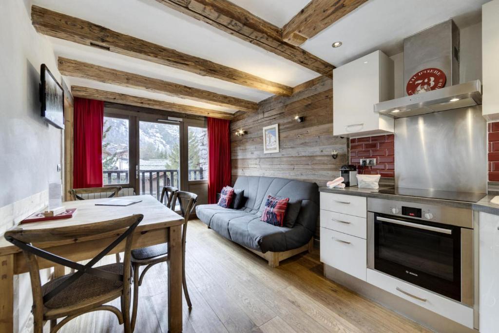 een keuken en een woonkamer met een tafel en een bank bij Residence Venus - 3 Pièces pour 4 Personnes 894 in Val dʼIsère