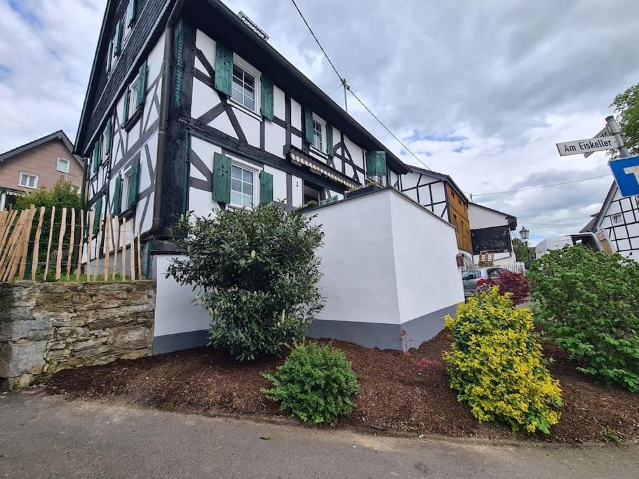 a black and white house with bushes in front of it at Ferienwohnung Bergischer Dreiklang in Windeck