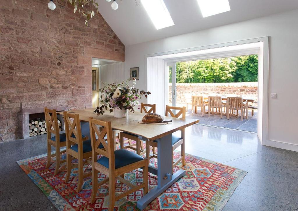 uma sala de jantar com mesa e cadeiras e uma parede de tijolos em Grieve's Cottage at Papple Steading em East Linton