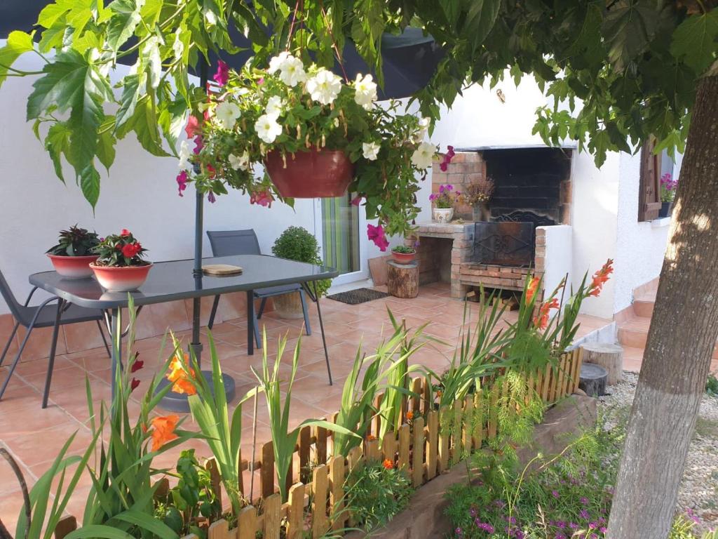 a patio with a table and flowers in a yard at Sous Les Chênes in Saint-Martin-de-Brômes
