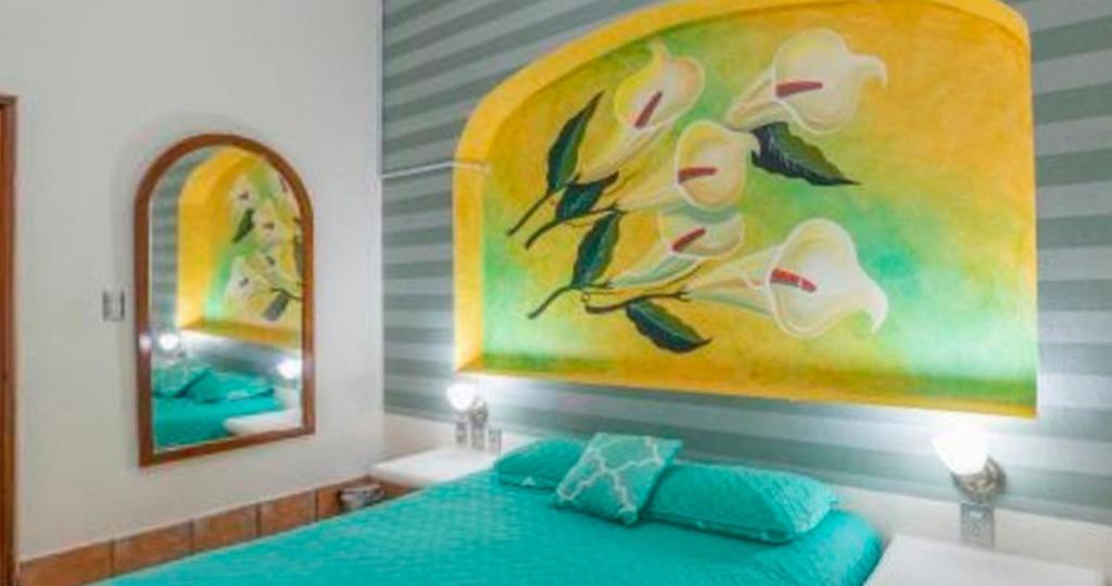 a bedroom with a blue bed and a painting on the wall at Hotel Yauco in Rosario