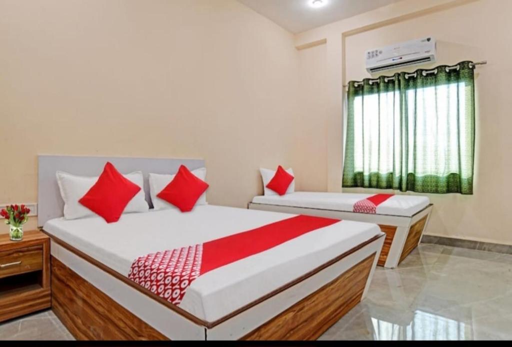 1 dormitorio con 2 camas y almohadas rojas en Paradise Inn, en Indore