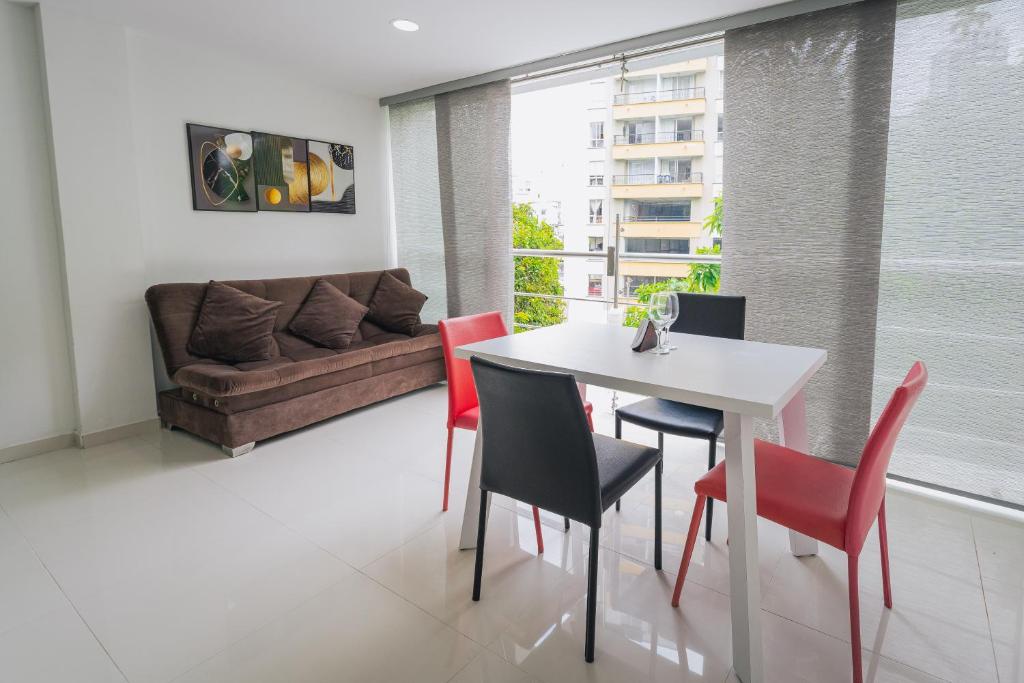 a dining room with a white table and red chairs at Exclusivo Apartaestudio en Pinares- 5 in Pereira