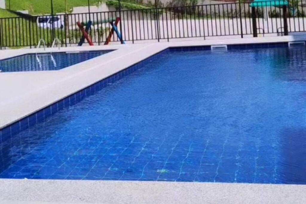 una gran piscina azul con una valla negra en Quarto privativo en Florianópolis