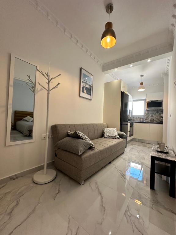 a living room with a couch and a tree in it at Eleni's Green balcony modern apartment by the Sea in Loutraki