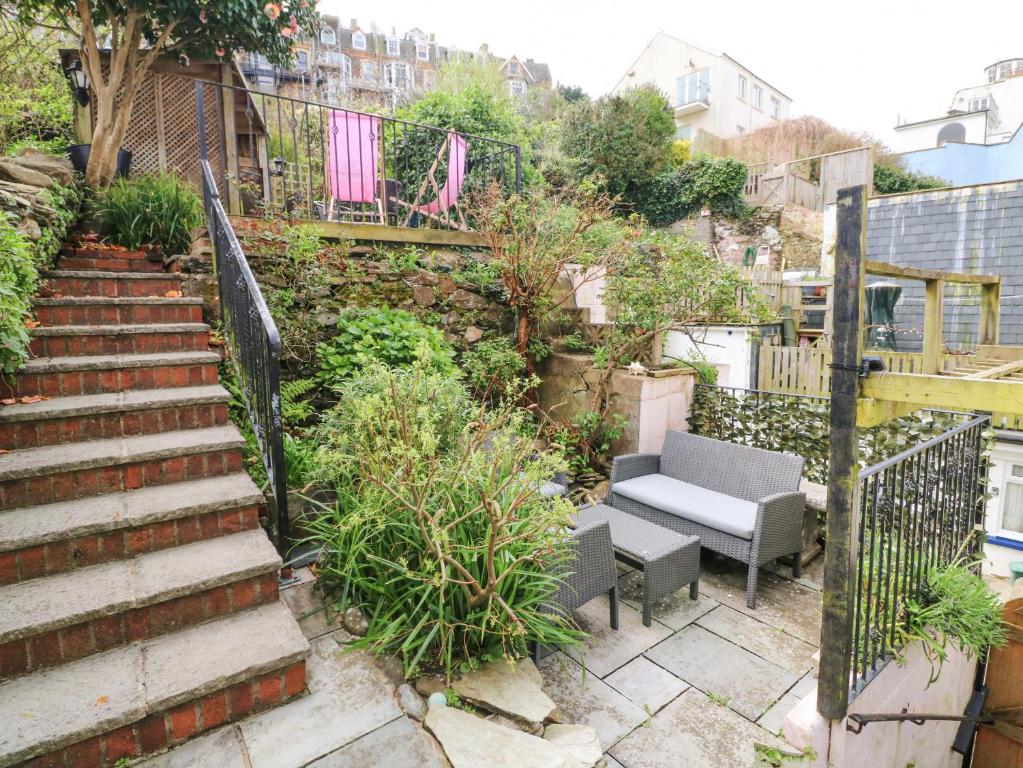 a stairway with a bench and chairs in a garden at Harbour Cottage in Ilfracombe