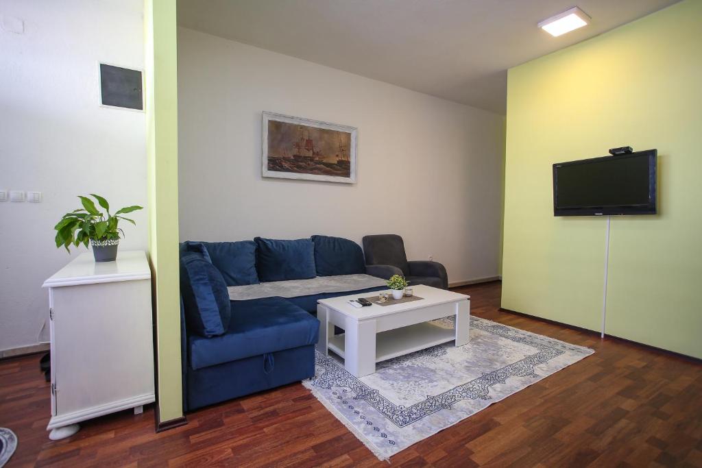 sala de estar con sofá azul y TV en Hercegovina 2 en Mostar