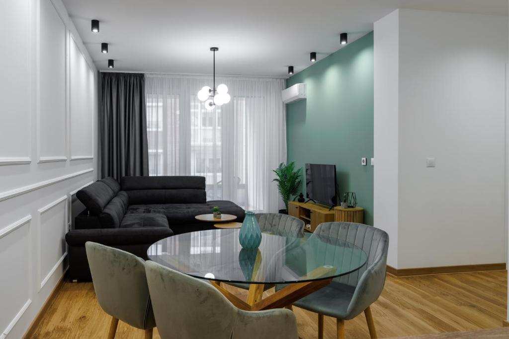 uma sala de estar com uma mesa de vidro e cadeiras em Apartment Simpatico em Novi Sad