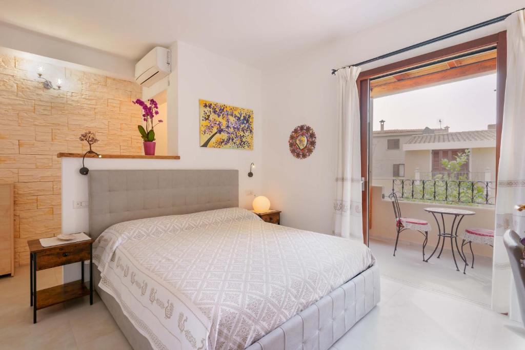 a bedroom with a bed and a balcony with a table at B&B Ametista in Villasimius